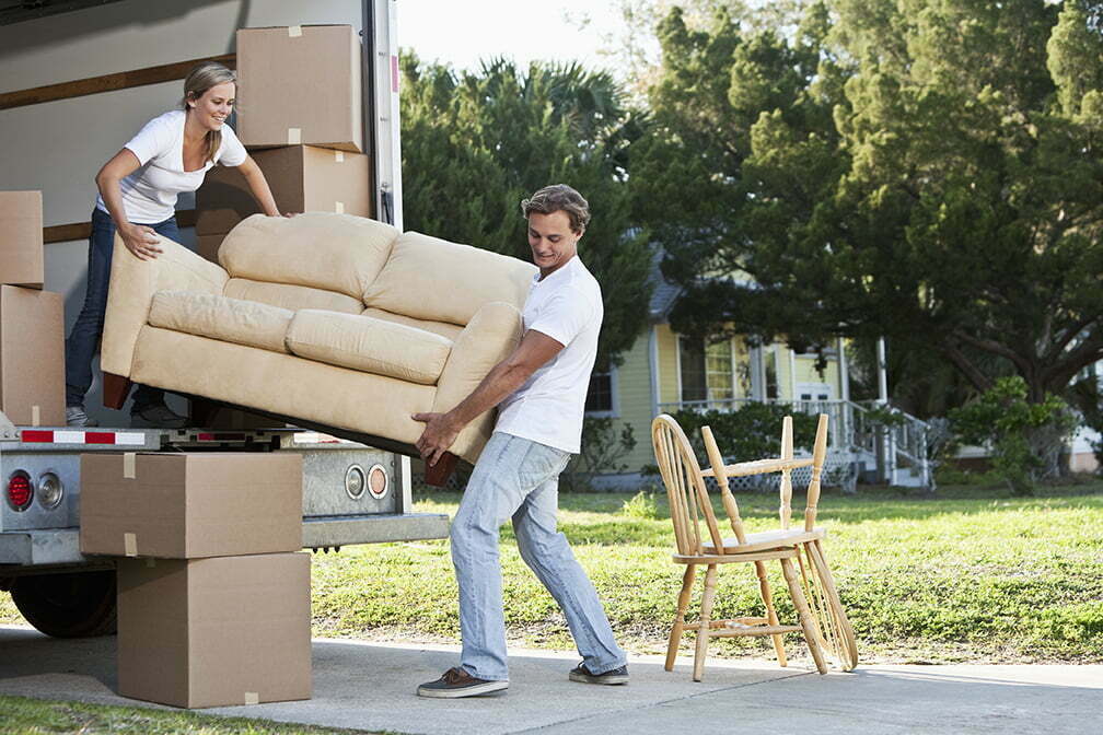 Couple moving house, loading or unloading couch in moving van