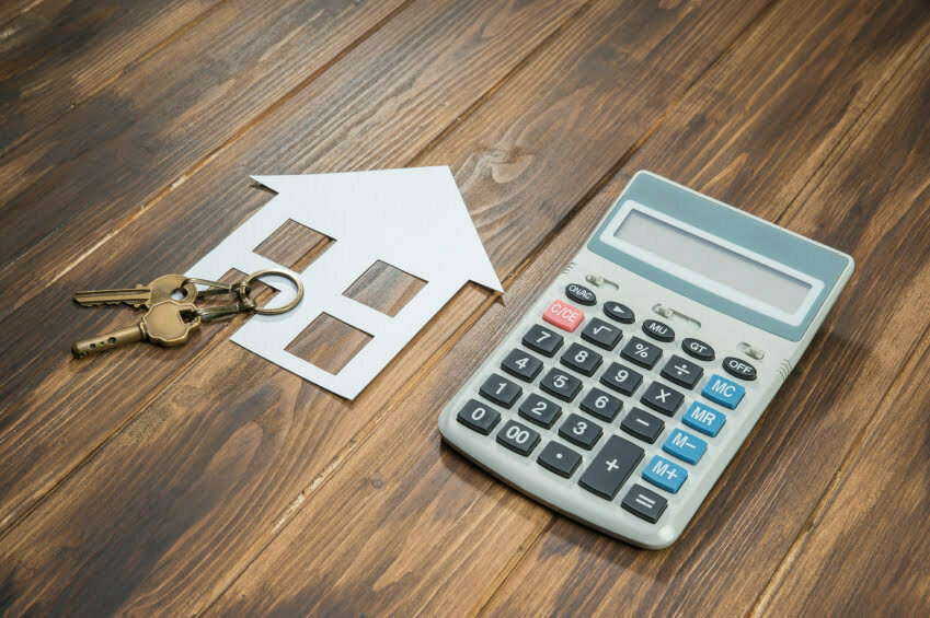 house and key with Calculator on wooden background